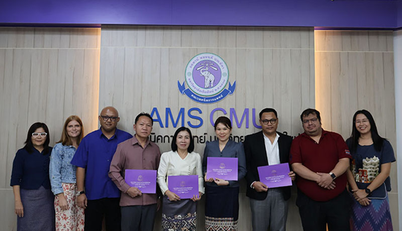 Participants in the closing ceremony gathered in a University classroom, posing in front of the University logo. Trainees hold their diplomas in their hands.