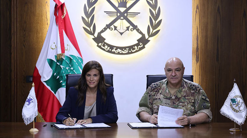 Dr Josette Najjar et Général Joseph Aoun are sitting next to each other, looking right into the camera while signing the agreement